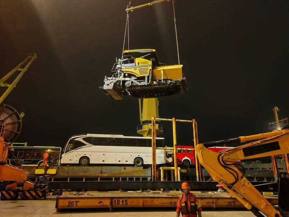 A shore crane lifting a construction machine during port loading